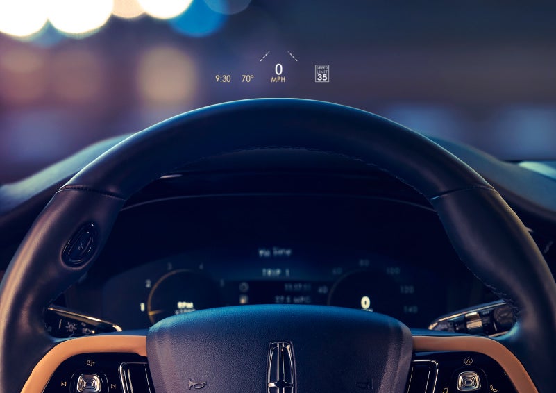 The available head-up display projects data on the windshield above the steering wheel inside a 2022 Lincoln Corsair as the driver navigates the city at night | Beck Lincoln in Palatka FL