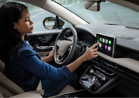 A woman in the driver’s seat of a 2022 Lincoln Corsair is touching the center digital screen to connect to Apple CarPlay<sup>®</sup> | Beck Lincoln in Palatka FL