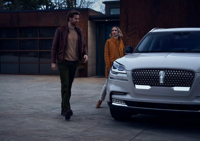 A man and a woman approaching a 2024 Lincoln Aviator® SUV, which illuminates certain lights when they are close | Beck Lincoln in Palatka FL